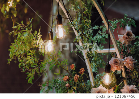 A beautiful wooden arch decorated with flowers and fairy lights 121067450