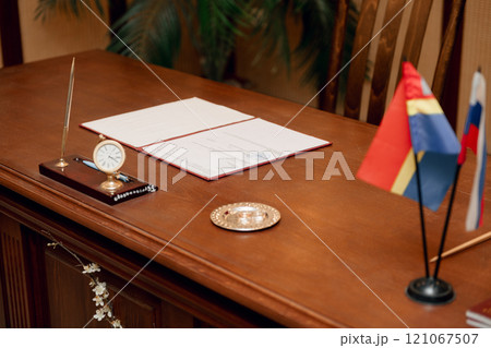 A wooden desk adorned with a clock and decorative flags 121067507