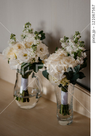 Two beautiful vases with vibrant white flowers sit on a counter 121067567