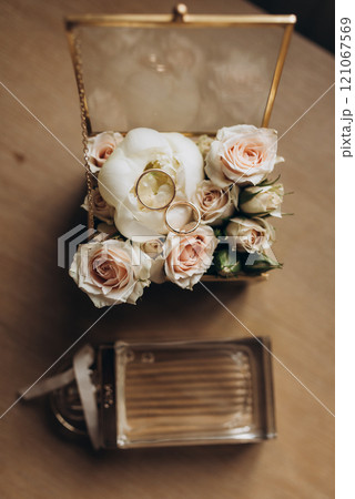 On a table there is a glass box filled with beautiful flowers and wedding rings 121067569