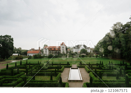 A large house is in the background with a maze in the front 121067571