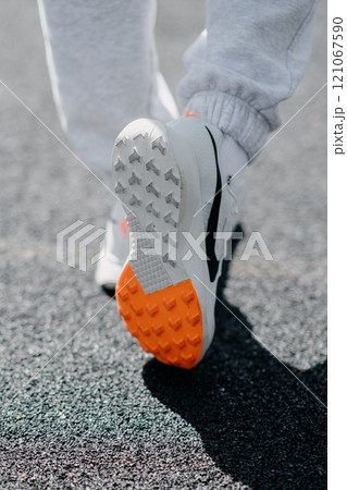 A person is wearing stylish white shoes with an orange sole A person is wearing stylish white shoes with an orange sole 121067590