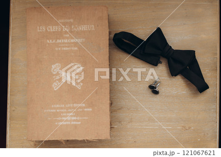On a sturdy wooden table, a book sits alongside a stylish bow tie On a sturdy wooden table, a book sits alongside a stylish bow tie 121067621