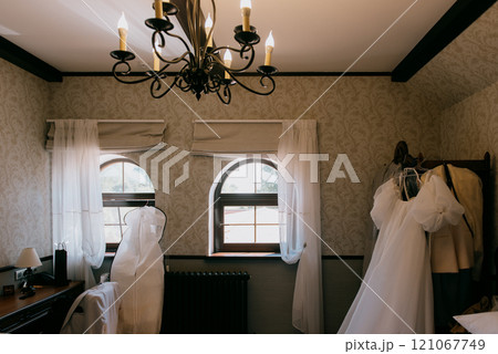 Two elegant wedding dresses hang beautifully under a chandelier Two elegant wedding dresses hang beautifully under a chandelier 121067749