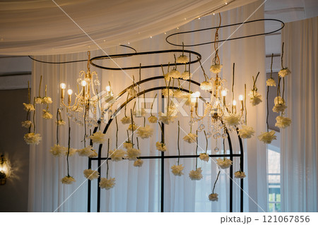 A chandelier decorated with flowers and candles hangs elegantly A chandelier decorated with flowers and candles hangs elegantly 121067856