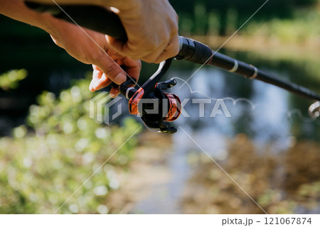 A person is firmly holding a fishing rod in their hand right now A person is firmly holding a fishing rod in their hand right now 121067874