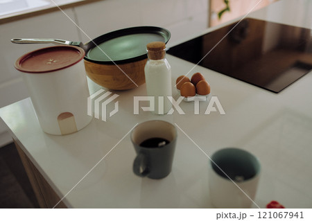 A kitchen counter with coffee, a bowl of eggs, and milk 121067941