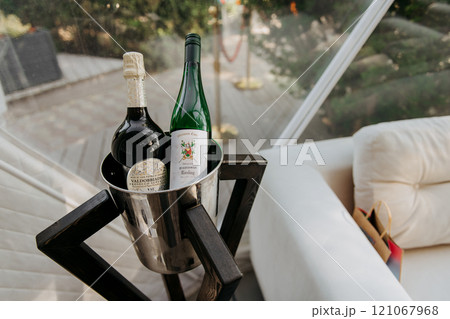 There are two bottles of wine placed inside a bucket on a table There are two bottles of wine placed inside a bucket on a table 121067968