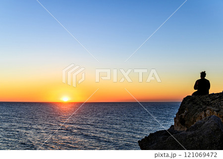Young man watching the sunset on the Barbate beach next to the Trafalgar lighthouse, Cadiz	 121069472
