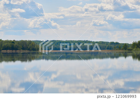 Experience the serene lakeside reflections beautifully painted under a softly cloudy sky 121069993