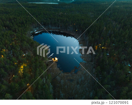 Experience a stunning aerial view of a serene forest lake at dusk with a beautiful sky Experience a stunning aerial view of a serene forest lake at dusk with a beautiful sky 121070091