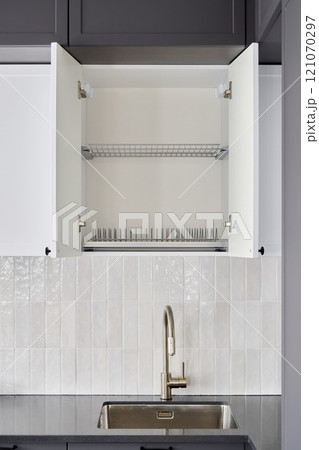 This is a modern kitchen cabinet featuring stylish design with open doors and a sleek sink 121070297