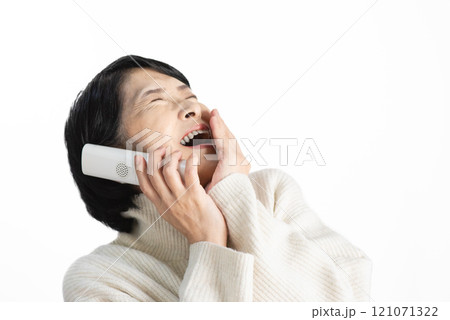 固定電話の子機を片手に大笑いする人物 121071322