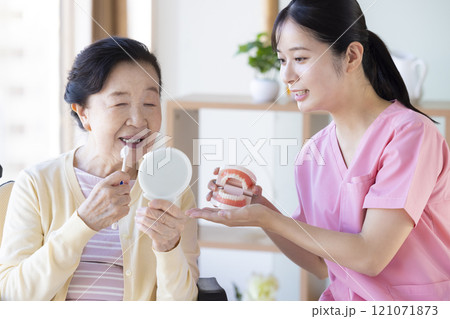 歯科衛生士から歯磨き指導を受けるシニア女性 121071873