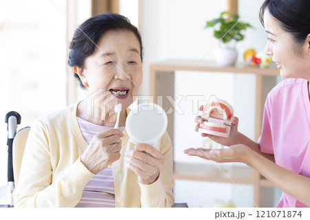 歯科衛生士から歯磨き指導を受けるシニア女性 121071874