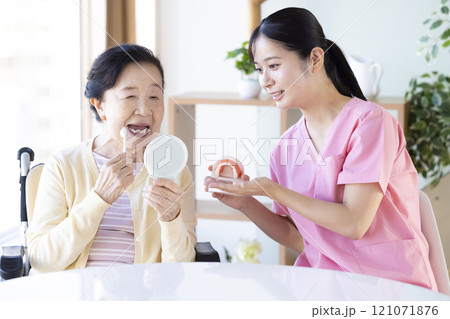 歯科衛生士から歯磨き指導を受けるシニア女性 歯科衛生士から歯磨き指導を受けるシニア女性 121071876