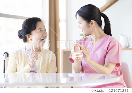 歯科衛生士から歯磨き指導を受けるシニア女性 121071881