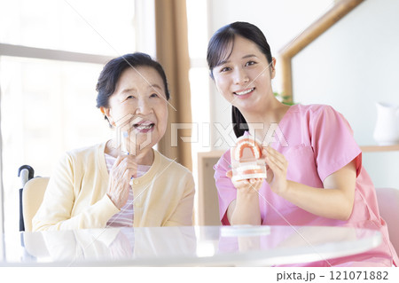 歯科衛生士から歯磨き指導を受けるシニア女性 121071882