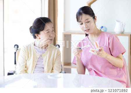 歯科衛生士から歯磨き指導を受けるシニア女性 121071892