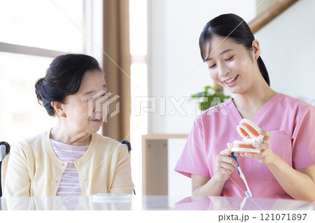 歯科衛生士から歯磨き指導を受けるシニア女性 歯科衛生士から歯磨き指導を受けるシニア女性 121071897