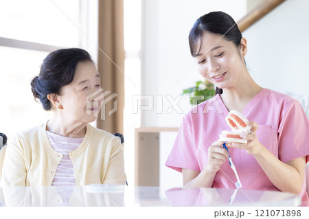 歯科衛生士から歯磨き指導を受けるシニア女性 歯科衛生士から歯磨き指導を受けるシニア女性 121071898