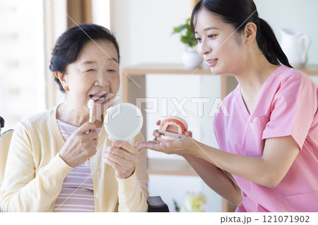 歯科衛生士から歯磨き指導を受けるシニア女性 121071902