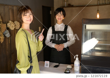 お店でスマホ決済する女性　 121072119