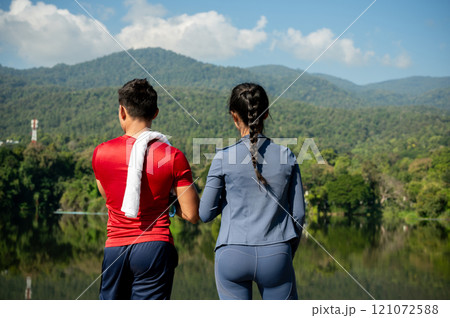 A back view of an Asian man and woman in sportswear, admiring the nature view in a park. A back view of an Asian man and woman in sportswear, admiring the nature view in a park. 121072588