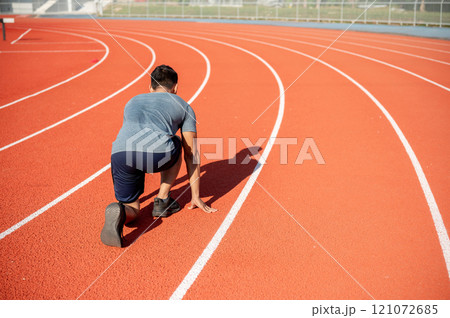 A strong Asian athletic male runner in sportswear trains at a stadium, preparing to run 121072685
