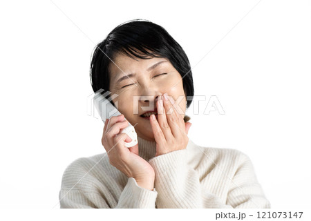 固定電話の子機を片手に笑う中年女性 121073147