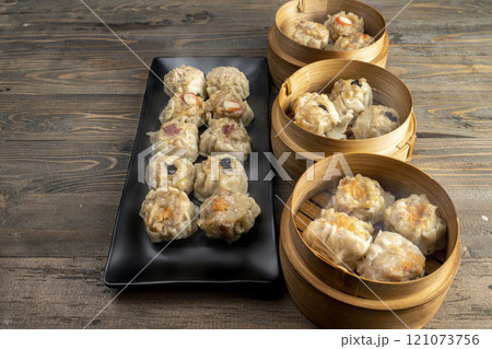 Assorted chinese dim sum dumpling on the plate with bamboo wooden basket bowl on wooden table Assorted chinese dim sum dumpling on the plate with bamboo wooden basket bowl on wooden table 121073756