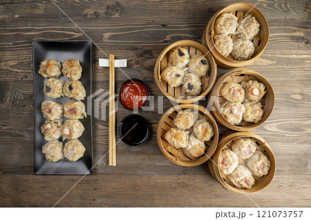 Assorted chinese dim sum dumpling on the plate with bamboo wooden basket bowl and chopstick with sauce on wooden table Assorted chinese dim sum dumpling on the plate with bamboo wooden basket bowl and chopstick with sauce on wooden table 121073757