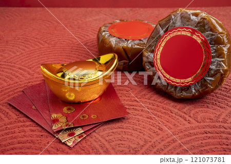 Chinese New Year rice cake or Nian Gao with angpao and Chinese gold ingot on a red background 121073781