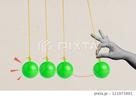 A human hand pulling a balancing ball on a pendulum on a colored background 121073801