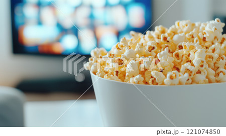 Popcorn in paper bucket on table with blurred TV screen in background, weekend home party Popcorn in paper bucket on table with blurred TV screen in background, weekend home party 121074850