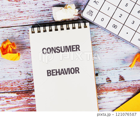 Notebook displaying consumer behavior notes on a wooden table with crumpled paper and a calculator 121076587