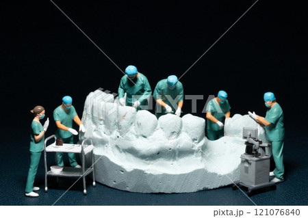 Miniature surgeons working on a dental model, showcasing the intricacies of dental procedures in a unique and artistic manner 121076840