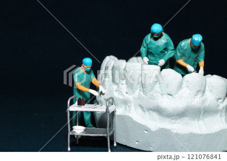 Miniature surgeons working on a dental model, showcasing the intricacies of dental procedures in a unique and artistic manner Miniature surgeons working on a dental model, showcasing the intricacies of dental procedures in a unique and artistic manner 121076841