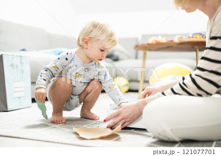 Parents playing games with child. Little toddler doing puzzle. Infant baby boy learns to solve problems and develops cognitive skills. Child development concept. 121077701