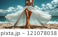 A beautiful female tourist in a light white dress walks along the beach. 121078038