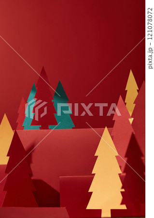 Crimson rectangular podium with product display space, set in a red background, surrounded by various paper pines with different colors. Warm-tone Christmas theme image template with bottom-up view. 121078072