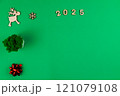 Spread on a green background chroma key, on the left there is a wooden deer with branchy antlers, a green office flower made of moss in a white pot and a red shiny gift bow, on top there is a wooden 121079108