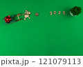 A wooden deer with branchy antlers is carrying a green wooden sleigh on which lies a red festive New Year's bow, in front of the deer there is a wooden snowflake and it is written 2025, in the corner 121079113