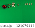 A wooden reindeer with branchy antlers is pulling a green wooden sleigh on which a red festive New Year's bow lies, a wooden snowflake lies in front of the deer and the year 2025 is written with space 121079114