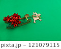 A wooden deer with antlers is carrying a green wooden sleigh on which there are red holiday bows, gifts on a bright green background. High quality photo 121079115