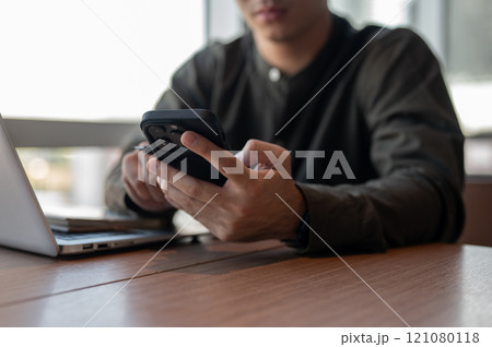 A close-up of a businessman using his smartphone at a table in the office. 121080118