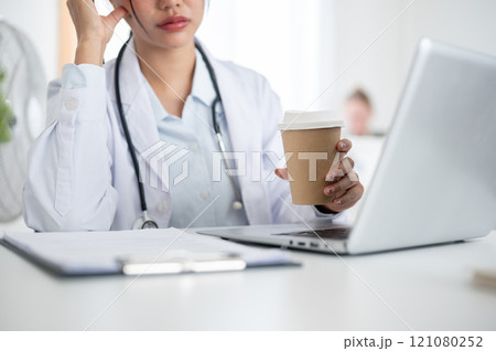 A professional, thoughtful Asian female doctor working at her desk in the office in the hospital. A professional, thoughtful Asian female doctor working at her desk in the office in the hospital. 121080252