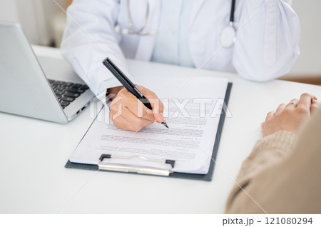 A close-up of a doctor filling out a medical form while examining a patient. A close-up of a doctor filling out a medical form while examining a patient. 121080294