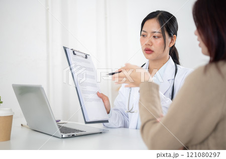 A doctor showing a medical paper to a patient while discussing the treatment plan at the hospital. 121080297