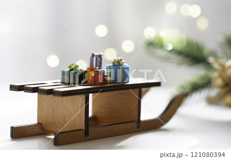 贈り物 ギフトのイメージ プレゼントの箱がのったミニチュアのそり モミの葉とイルミネーション 贈り物 ギフトのイメージ プレゼントの箱がのったミニチュアのそり モミの葉とイルミネーション 121080394